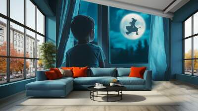 child looking out the window at a witch flying under the light of the full moon on halloween night Wall mural