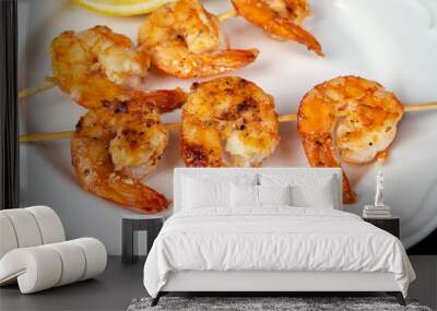 Delicious roasted shrimps on skewers arranged in a white plate with lemon slice and fresh rosemary on a black background close up Wall mural