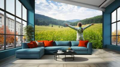 Little girl on the background of a blossomed yellow field with wild peonies Wall mural