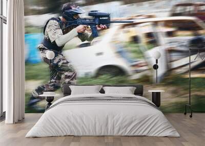 Paintball, aim and man with a gun for a game with blur motion at an outdoor arena or field. Challenge, competition and male soldier with a camouflage military outfit shooting a rifle on a battlefield Wall mural