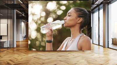 Take breaks when you need to replenish your energy. Shot of a sporty young woman drinking water while exercising outdoors. Wall mural