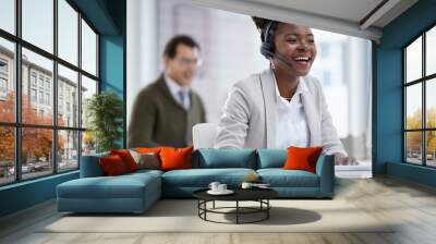 The agent who knows it all. Shot of a young businesswoman wearing a headset while working on a computer in an office. Wall mural