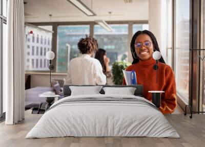 Black girl in office in foreground is looking at camera Wall mural