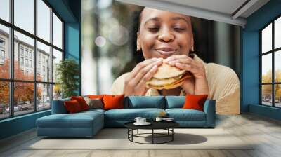 Restaurant, fast food and black woman eating a burger in an outdoor cafe as a lunch meal craving deal. Breakfast, sandwich and young female person or customer enjoying a tasty unhealthy snack Wall mural