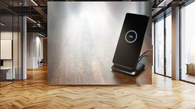 smartphone wireless charging on charging stand with 100 percent icon on screen on wooden table Wall mural