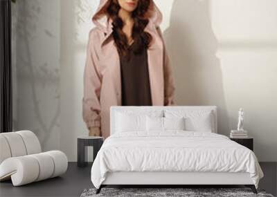 Female model wearing trendy spring outfit, pink raincoat against white background. Spring, summer fashion concept Wall mural