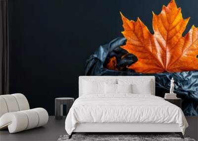  A black trashcan with an orange leaf protruding from its top against a dark backdrop Wall mural