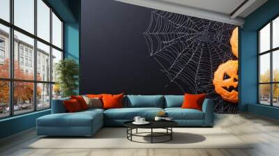  A collection of orange pumpkins carved with jack-o-lantern faces dangles from a spider web Wall mural