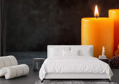  A couple of candles atop a table, surrounded by a single pine cone and another bearing a flower Wall mural