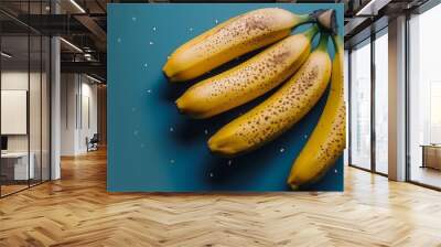   A group of ripe bananas resting on a blue surface with water droplets beneath Wall mural