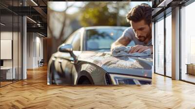  A man wipes down a car hood, towel atop, house in background Wall mural