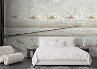   A pair of knitting needles atop a pristine white knitted blanket, accompanied by white balls of yarn Wall mural