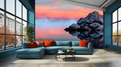  A pink and blue sky backs this body of water's midpoint rock formation Wall mural