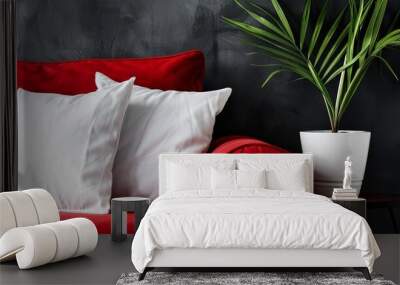  A red couch with two white pillows and a plant in a white vase on a nearby small table Wall mural