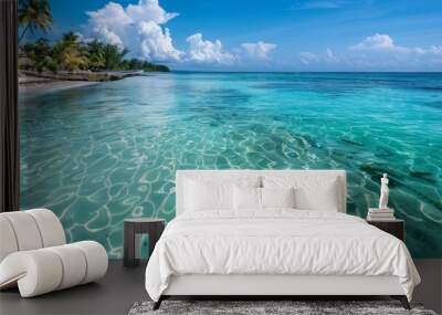  A tranquil body of water with a sandy shore, palm trees lining the opposite edge, and a blue sky dotted with fluffy white clouds above Wall mural