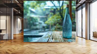  A water bottle atop a wooden table, near a swimming pool and framed by trees in the background Wall mural