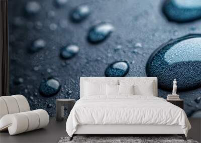  Close-up of water droplets on a black surface against a blue sky backdrop, with additional drops of water present Wall mural