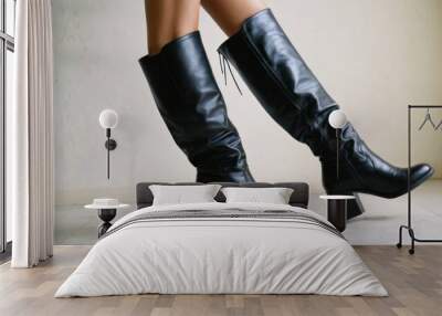  The image shows a person standing in a room, wearing boots with high heels. The boots are black and appear to be stylishly. Wall mural