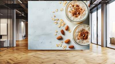  Three glasses of oatmeal with almonds on a pristine white surface, surrounded by a few scattered oats Wall mural