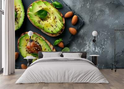  Two slices of bread topped with avocado and nuts on a slate platter Surrounded by green leaves and additional nuts as a side Wall mural