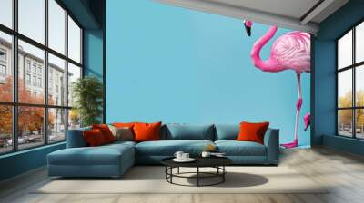 a pink flamingo standing on its hind legs on a blue background with its head turned to the side and it's legs in the air. Wall mural