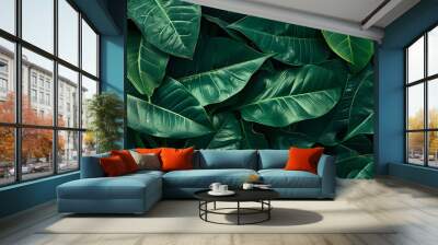 A nature background featuring an abstract green leaf texture. The image showcases dark green tropical leaves in close-up, revealing layered textures and various elements of tropical flora. Wall mural