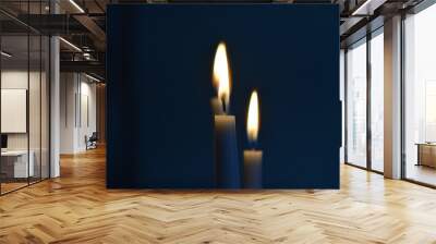 Closeup shot of two lit candles slowly burning in a dark room Wall mural