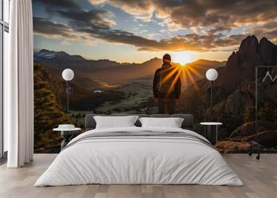 Male traveler standing in a cave with a view of rocky mountains at sunrise Wall mural