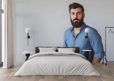 A bearded man in a blue shirt exudes charm and confidence against a white studio backdrop. Wall mural