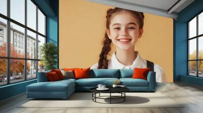 A cheerful and pleased schoolgirl model posing on a beige background, suitable for education, back to school, fashion, and lifestyle concepts. Wall mural