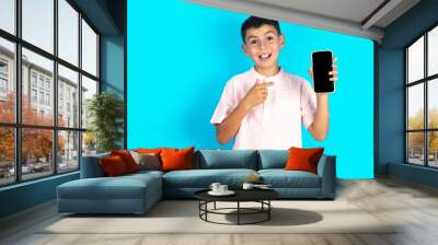 Attractive cheerful Little hispanic boy wearing white shirt  holding in hands cell showing black screen Wall mural