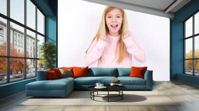 beautiful caucasian little girl wearing pink hoodie over white backgro rejoicing success and victory clenching his fists with joy being happy to achieve her aim and goals. Positive emotions, feelings. Wall mural