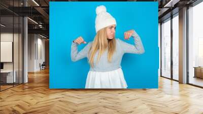 beautiful caucasian teen girl wearing grey sweater showing arms muscles smiling proud. Fitness concept. Wall mural