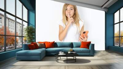 beautiful caucasian teen girl wearing white T-shirt over white wall holding modern gadget ask not tell secrets Wall mural