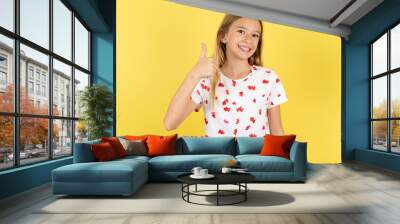 Beautiful teen girl doing happy thumbs up gesture with hand. Approving expression looking at the camera showing success. Wall mural