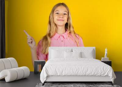 Positive Beautiful caucasian kid girl wearing pink shirt with satisfied expression indicates at upper right corner shows good offer suggests to click on link Wall mural