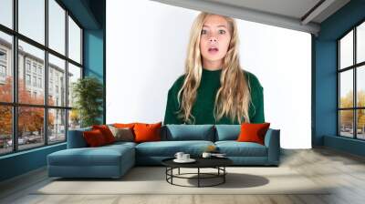 Shocked beautiful caucasian teen girl wearing green knitted sweater over white wall stares bugged eyes keeps mouth opened has surprised expression. Omg concept Wall mural