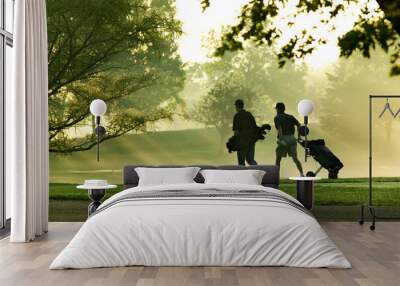 Two men golfers walking on a golf course with the sun streaking through the trees on a beautiful summer morning Wall mural