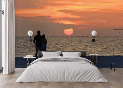 Beach lovers watch the sunset over Sanibel Island from Fort Myers Beach, Florida, USA. Wall mural