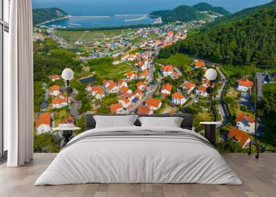 Mulgeon-ri, Namhae-gun, Gyeongsangnam-do, South Korea - June 18, 2023: Aerial and summer view of houses with orange roof at German Village on the hill against Mulgeon Port and sea 
 Wall mural