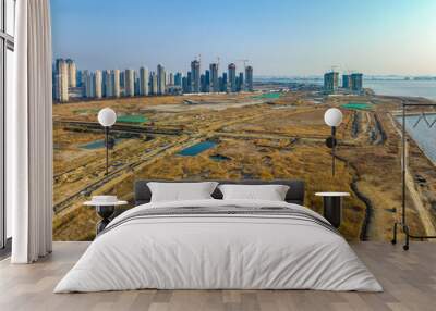 Songdo-dong, Yeonsu-gu, Incheon, South Korea - March 5, 2023: Aerial and winter view of reclaimed land with apartments and tower cranes at construction site near the sea
 Wall mural