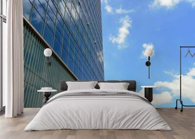 a low angle shot modern building with blue sky and clouds reflected in windows, in horizontal form Wall mural