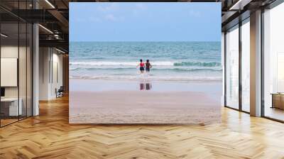 Back view of happy carefree couple holding hands and running in water at beach. Couple plays in ocean waves. Happy young couple playing in sea water. Guy and girl splashing together, beach vacation. Wall mural