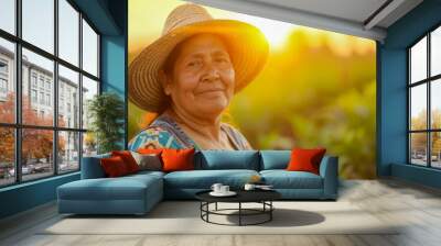 Latina female farmer with straw hat against blurred sunset background, food production concept Wall mural