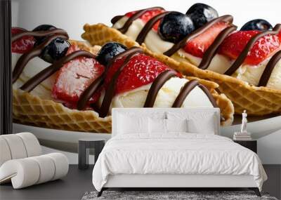 Two waffle bowls filled with ice cream, topped with strawberries, blueberries, and drizzled with chocolate sauce, served on a white plate. Wall mural