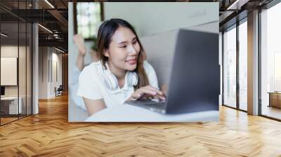 asian teenage girl using computer and wearing headphones at sofa Wall mural