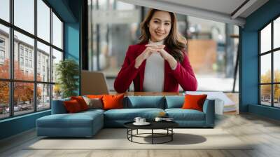 Portrait of a woman business owner showing a happy smiling face as he has successfully invested her business using computers and financial budget documents at work Wall mural