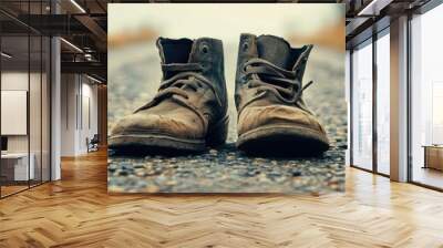 A pair of worn-out boots on a gravel road, symbolizing adventure, journey, and resilience in the great outdoors. Wall mural