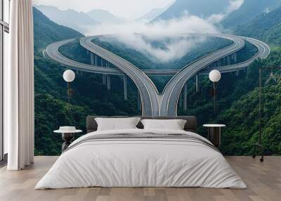 Aerial view of a winding highway through lush green mountains and clouds. Wall mural