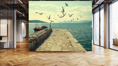 Scenic dock with boats and seagulls above the tranquil water under a blue sky. Wall mural